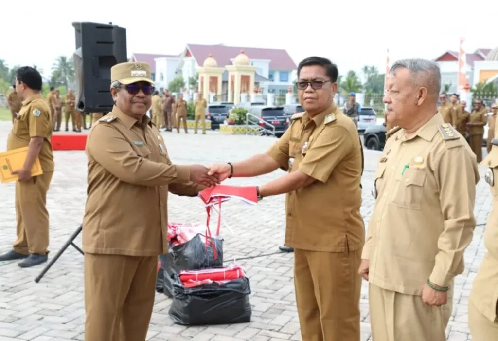 FOTO: Penjabat Bupati Aceh Utara Dr Drs Mahyuzar, MSi, menyerahkan Bendera kepada para Camat