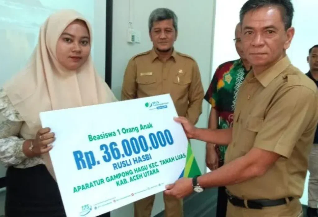 Foto: Penjabat Sekda Kabupaten Aceh Utara Dayan Albar, SSos, MAP, menyerahkan santunan kematian dan beasiswa kepada ahli waris dari keluarga aparatur gampong yang meninggal dunia.