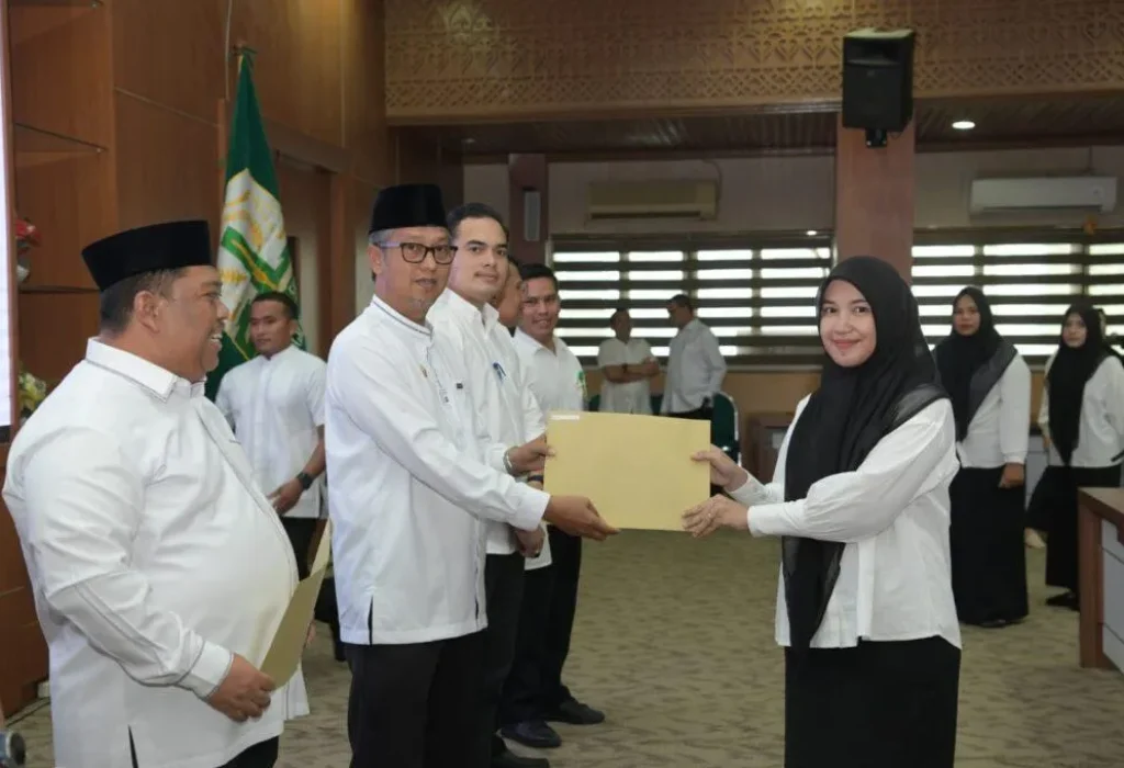 Foto: Asisten Administrasi Umum Sekda Aceh Dr. H. Iskandar AP, S.Sos. M.Si menyerahkan Sk tenaga kontrak kepada salah satu tenaga kontrak pada biro Adpim di gedung serbaguna Kantor Gubernur, Jum'at 22 Maret 2024.