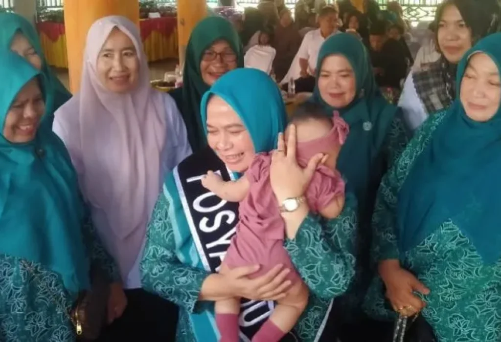 Foto: Pj Ketua TP PKK Aceh Utara Ny Awirdalina Mahyuzar, mengendong balitas usai melakukan timbang berat badan