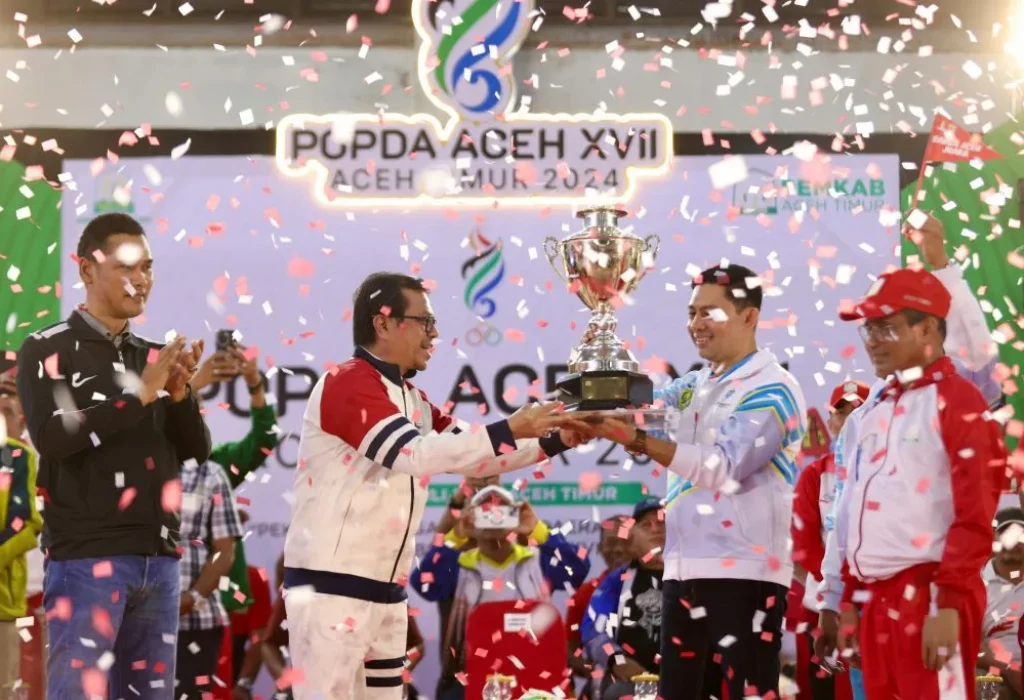 Foto: Penjabat Sekretaris Daerah Aceh, Azwardi AP, M.Si., atas nama PJ Gubernur Aceh menyerahkan piala bergilir kepada Kota Banda Aceh yang keluar sebagai juara umum  pada Pekan Olahraga Pelajar Daerah (POPDA) Aceh ke-XVII Tahun 2024, Di Gedung Idi Sport Center (ISC), Aceh Timur, Jumat, 12/7/2024.