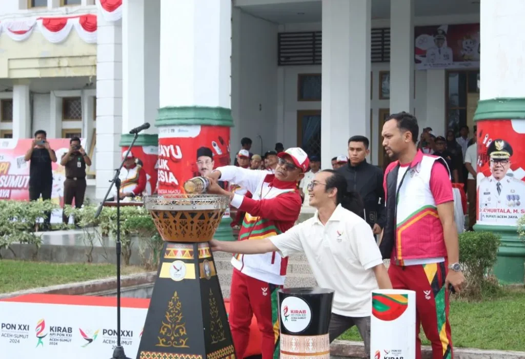 Foto: Pj. Bupati Aceh Jaya, Dr. A. Murtala menyalakan kembali Api untuk diserahkan kembali kepada pelari kirab Api PON XXI di halaman Kantor Bupati Aceh Jaya, 27/8/2024