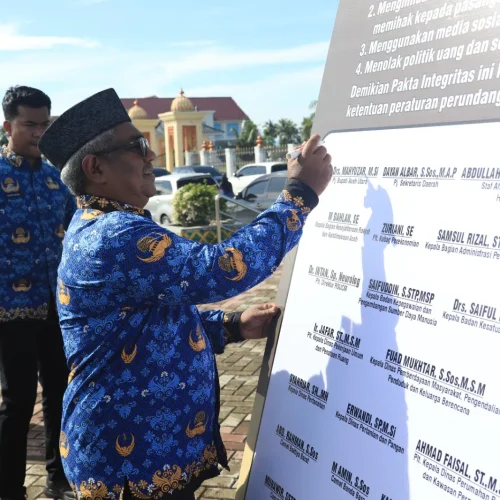 Foto: Pj Bupati Mahyuzar menandatanganan prasasti ikrar netralitas ASN pada bentangan spanduk di lapangan upacara