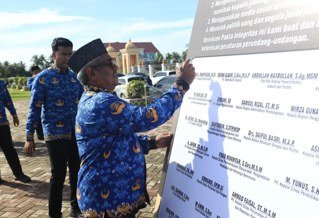 Foto: Pj Bupati Mahyuzar menandatanganan prasasti ikrar netralitas ASN pada bentangan spanduk di lapangan upacara